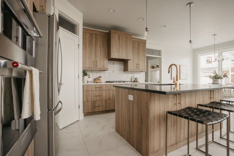 Modern kitchen with wood cabinetry, black countertops, and pendant lighting