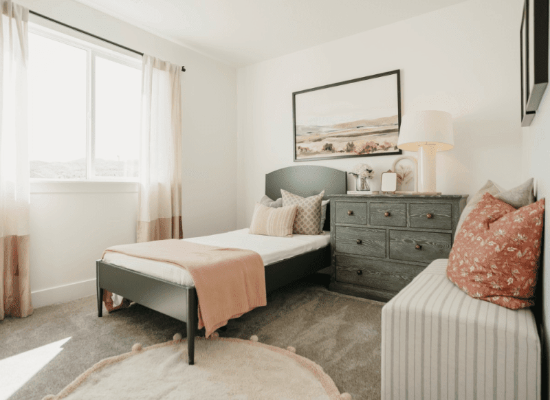 A decluttered bedroom with natural lighting pouring in through the window