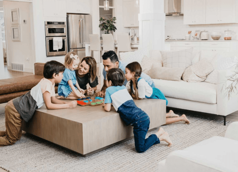 A family gathering around a coffee table playing a game in their new home