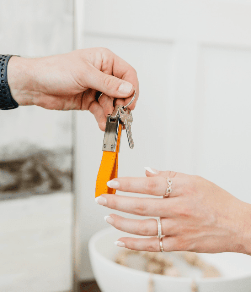 A man handing off a set of keys to a woman’s hand, representing new homeownership