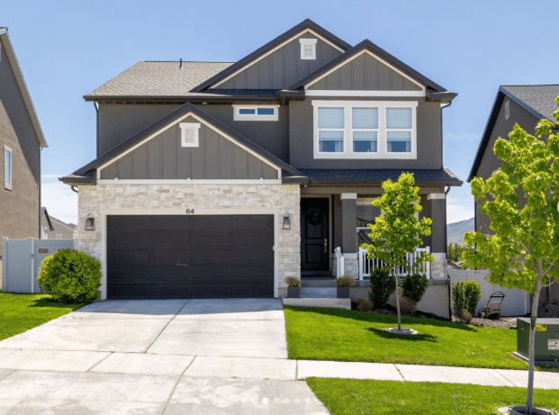 A newly built home by EDGEhomes surrounded by a green lawn, green trees, and a blue sky